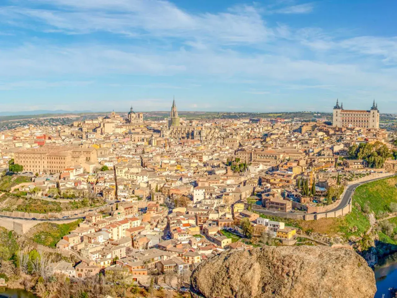 Toledo co zobaczyć: rozległa panorama miasta z katedrą i Alcázarem na wzgórzu, otoczona rzeką.