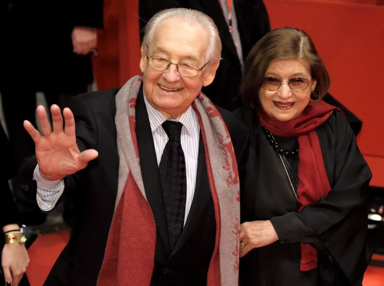 Andrzej Wajda z żoną, Krystyną Zachwatowicz, na czerwonym dywanie. Uśmiechnięci, elegancko ubrani, pozdrawiają publiczność.