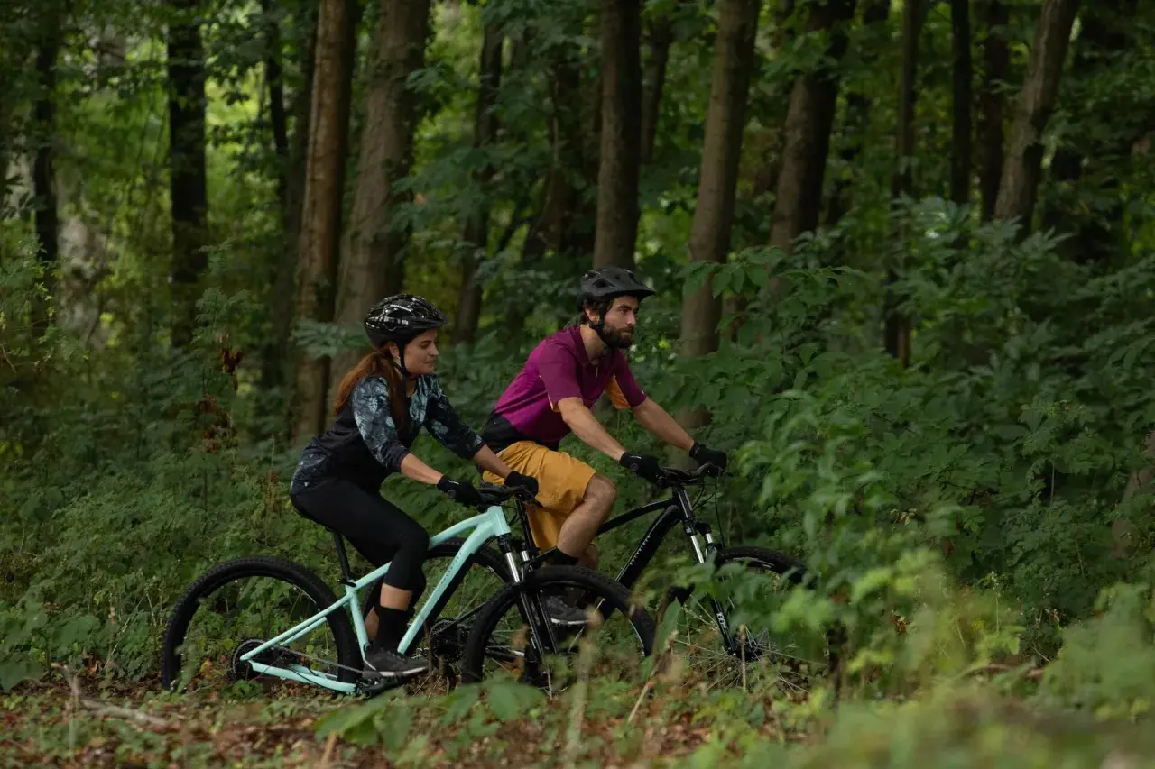 Para jadąca na rowerach górskich przez las. Czy to gravel, czy MTB? Wybór należy do nich.