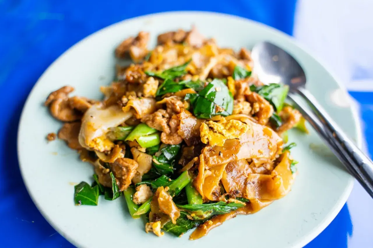 En tallrik med pad see ew, en klassisk thailändsk nudelrätt med breda risnudlar, ägg, grönsaker och kött.