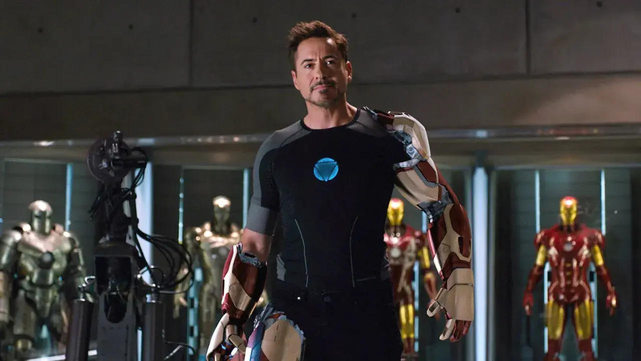 Tony Stark, czyli Iron Man, w swojej zbrojowni, otoczony przez kilka swoich pancerzy.