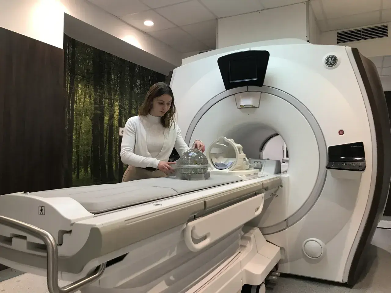 Kobieta przy aparacie MRI, przygotowująca fantom do badań. Praca w dziedzinie fizyki medycznej.