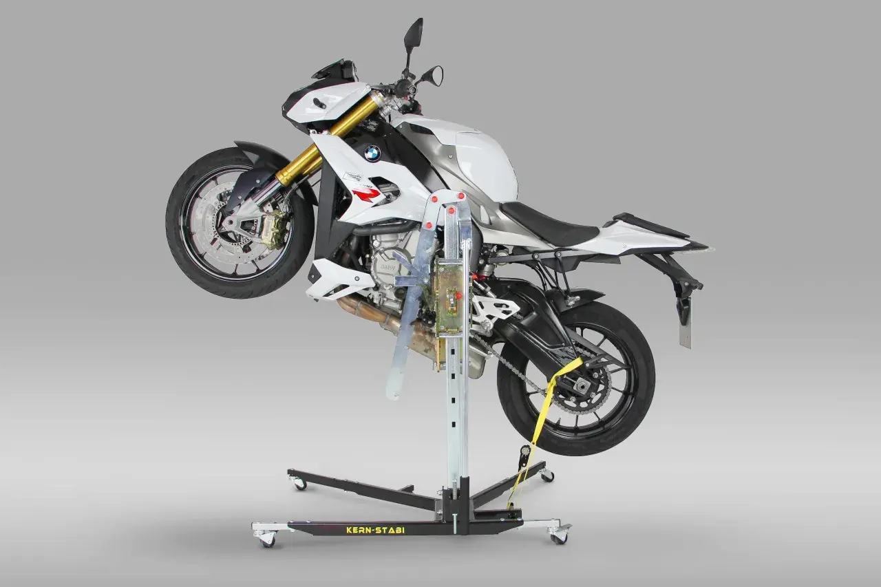 Biały motocykl BMW uniesiony na podnośniku motocyklowym centralnym.