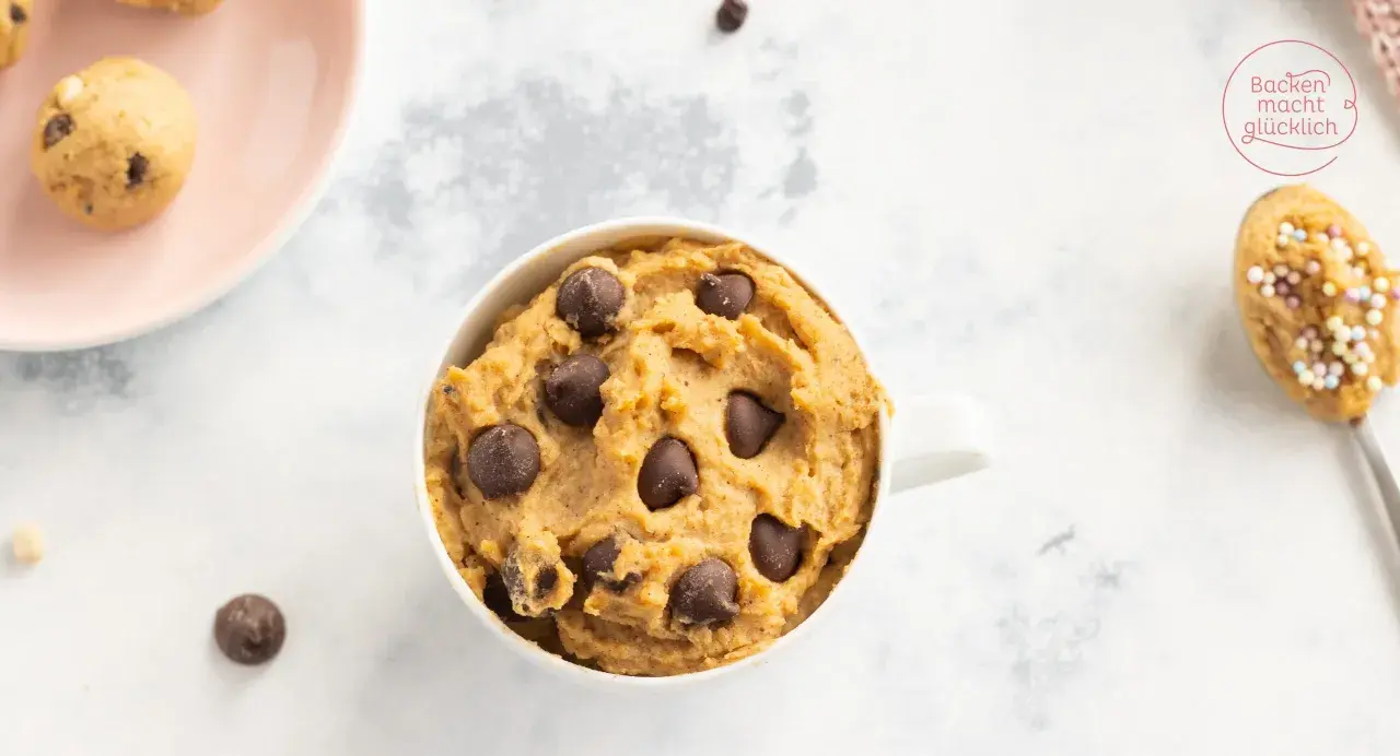 Leckeres Protein Cookie Dough Rezept in einer Tasse, mit Schokostückchen und auf einem Löffel mit Streuseln.