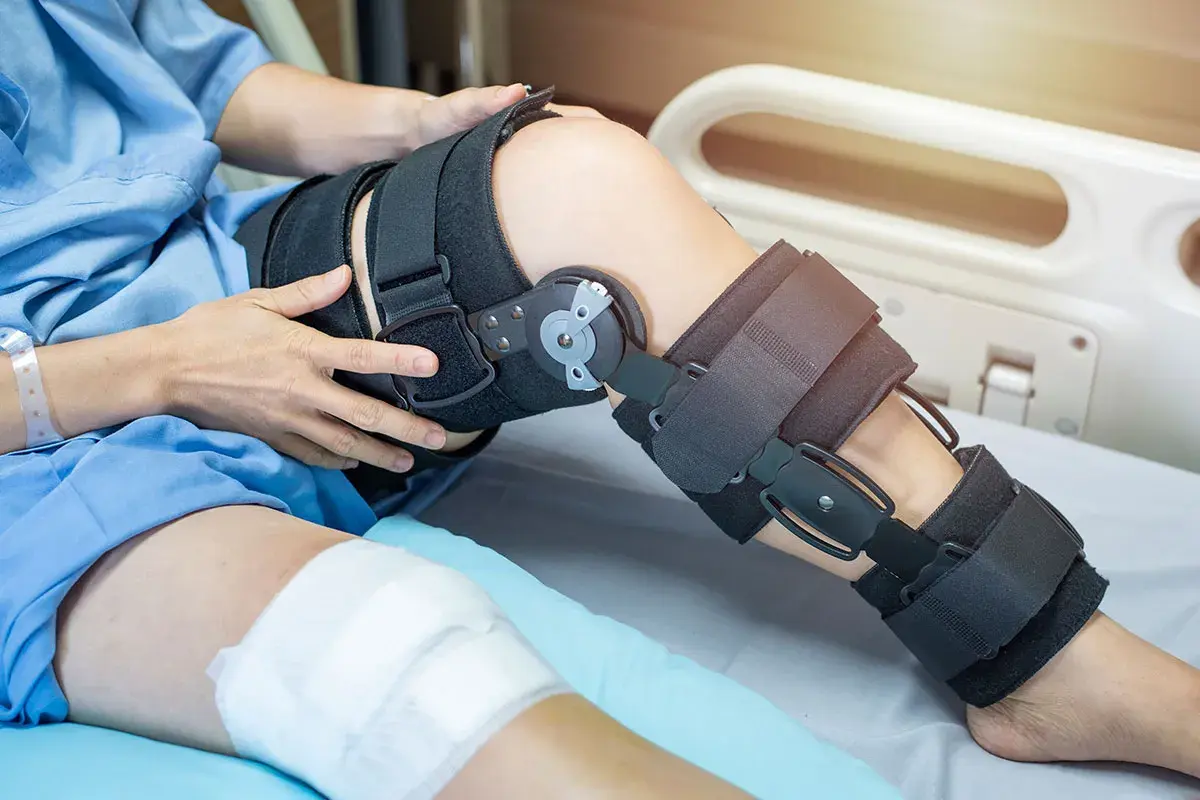 Patient mit Knieorthese, die von der Krankenkasse bezahlt wird, liegt im Krankenhausbett.