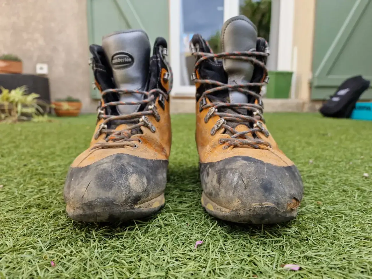 Bottes de randonnée usées, prêtes à être ressemelées. Elles ont vu du terrain et méritent une seconde vie.