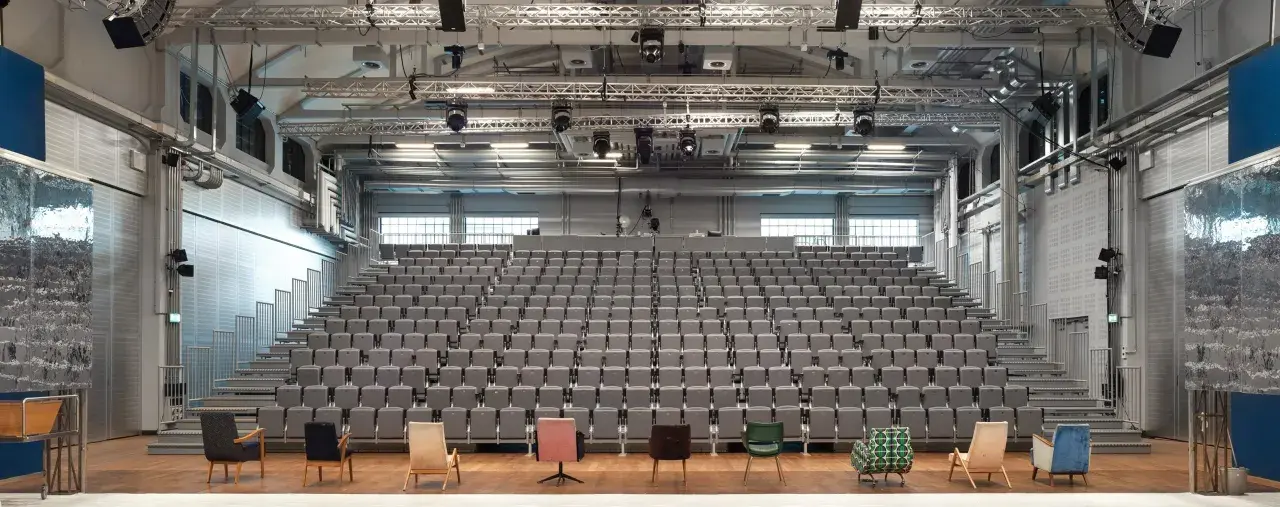 Widownia i scena Teatru Nowego w Warszawie. Puste, szare fotele czekają na widzów.
