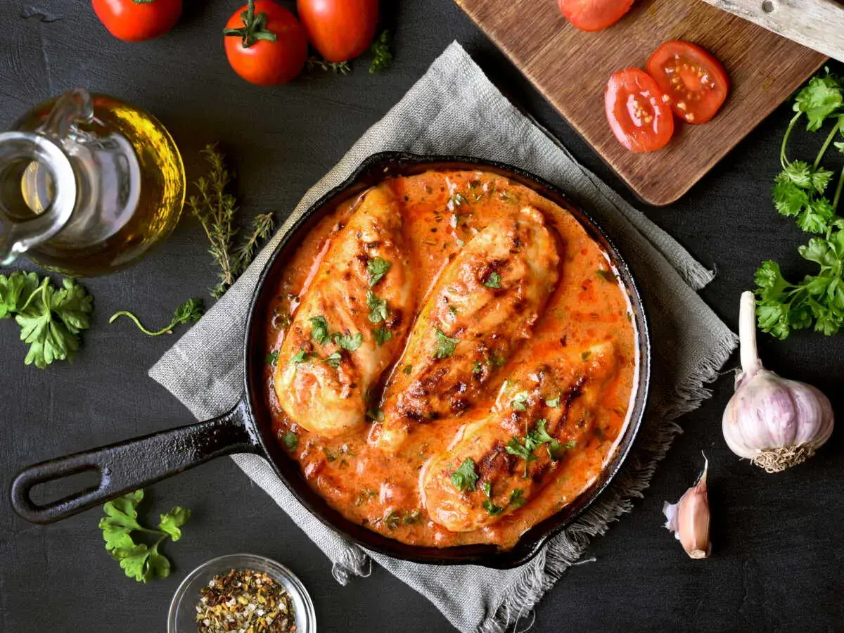 Poitrines de poulet en sauce crémeuse à la tomate, parsemées de persil. Un plat savoureux qui rappelle le poulet chorizo.