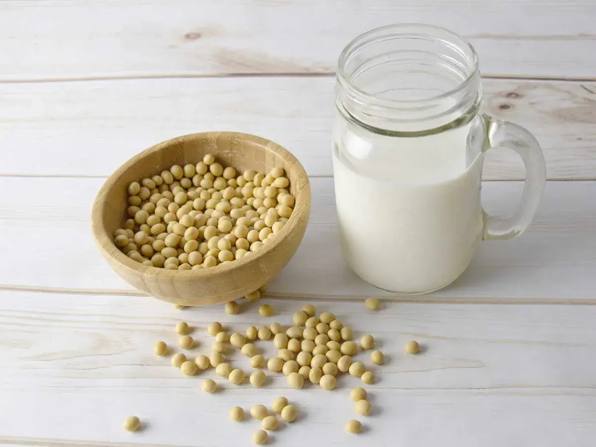 Bol en bois rempli de graines de soja, à côté d'un verre de lait de soja. La lécithine de soja est un ingrédient clé.
