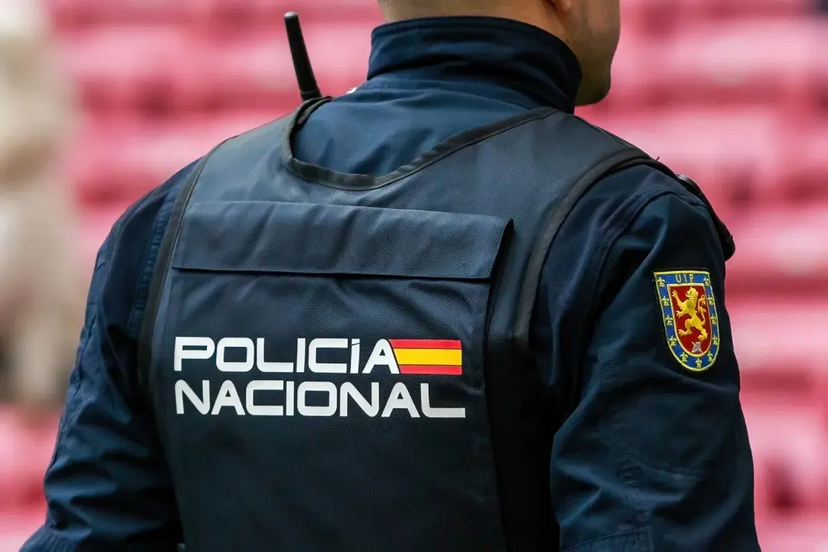 Policjant w kamizelce z napisem "POLICIA NACIONAL" i flagą Hiszpanii. Służba w policji Hiszpanii to odpowiedzialność.
