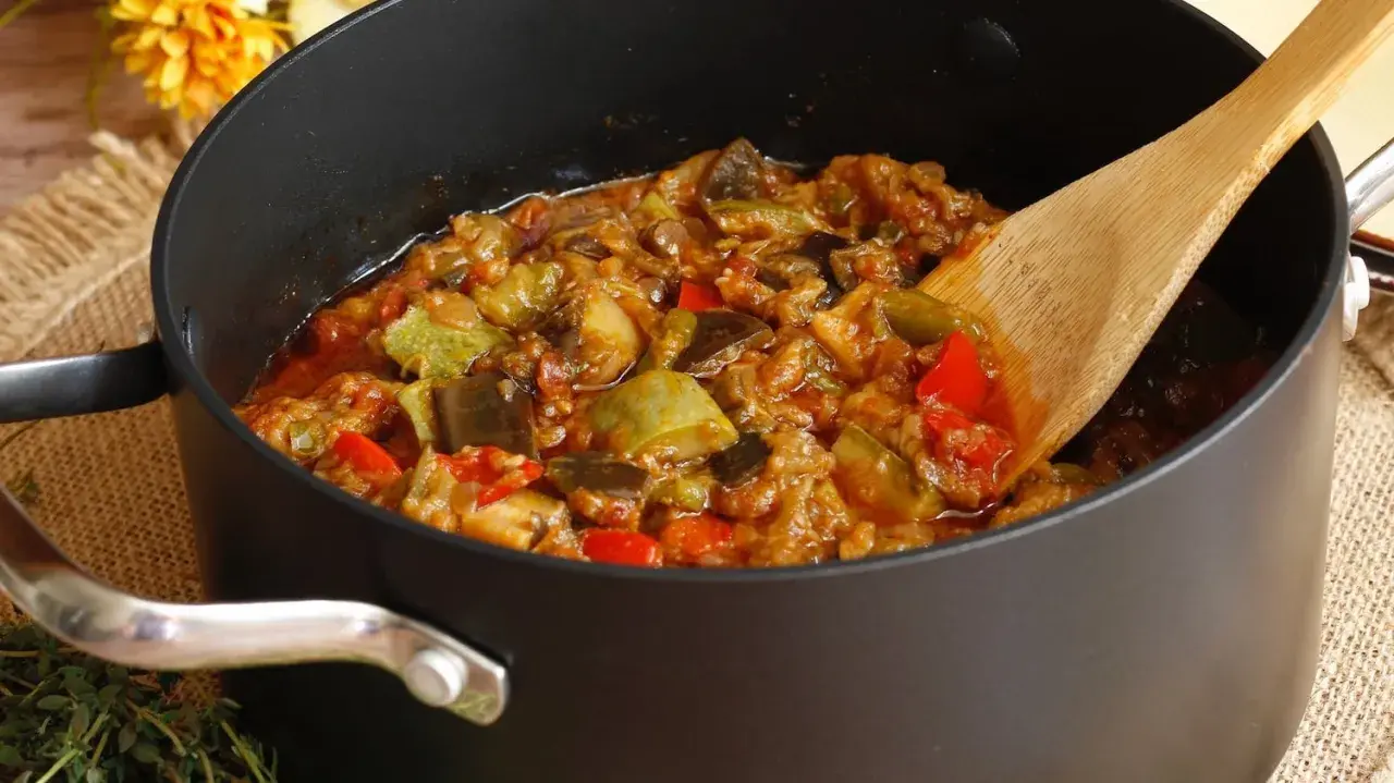 Une poêle remplie de ratatouille, comme dans le film, avec des légumes colorés et une cuillère en bois.
