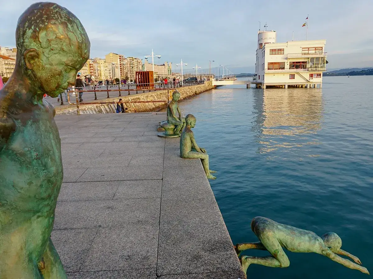 Los raqueros, esculturas de bronce, observan el mar desde el paseo marítimo. Uno se lanza al agua, otro espera sentado.