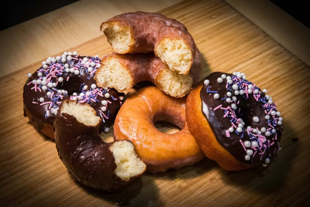 Deliciosos donuts caseros, algunos cubiertos de chocolate y chispas, otros glaseados, listos para disfrutar.