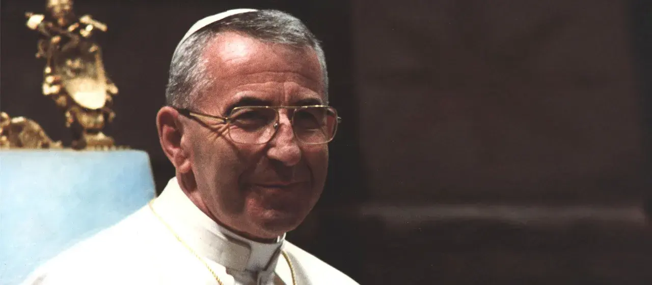 Porträt von Papst Johannes Paul I. mit Brille, im Hintergrund eine goldene Statue.
