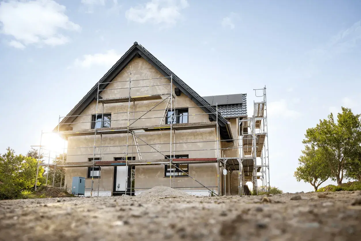 Maison en construction avec échafaudages. Le chantier laisse imaginer le futur prix de rénovation maison.