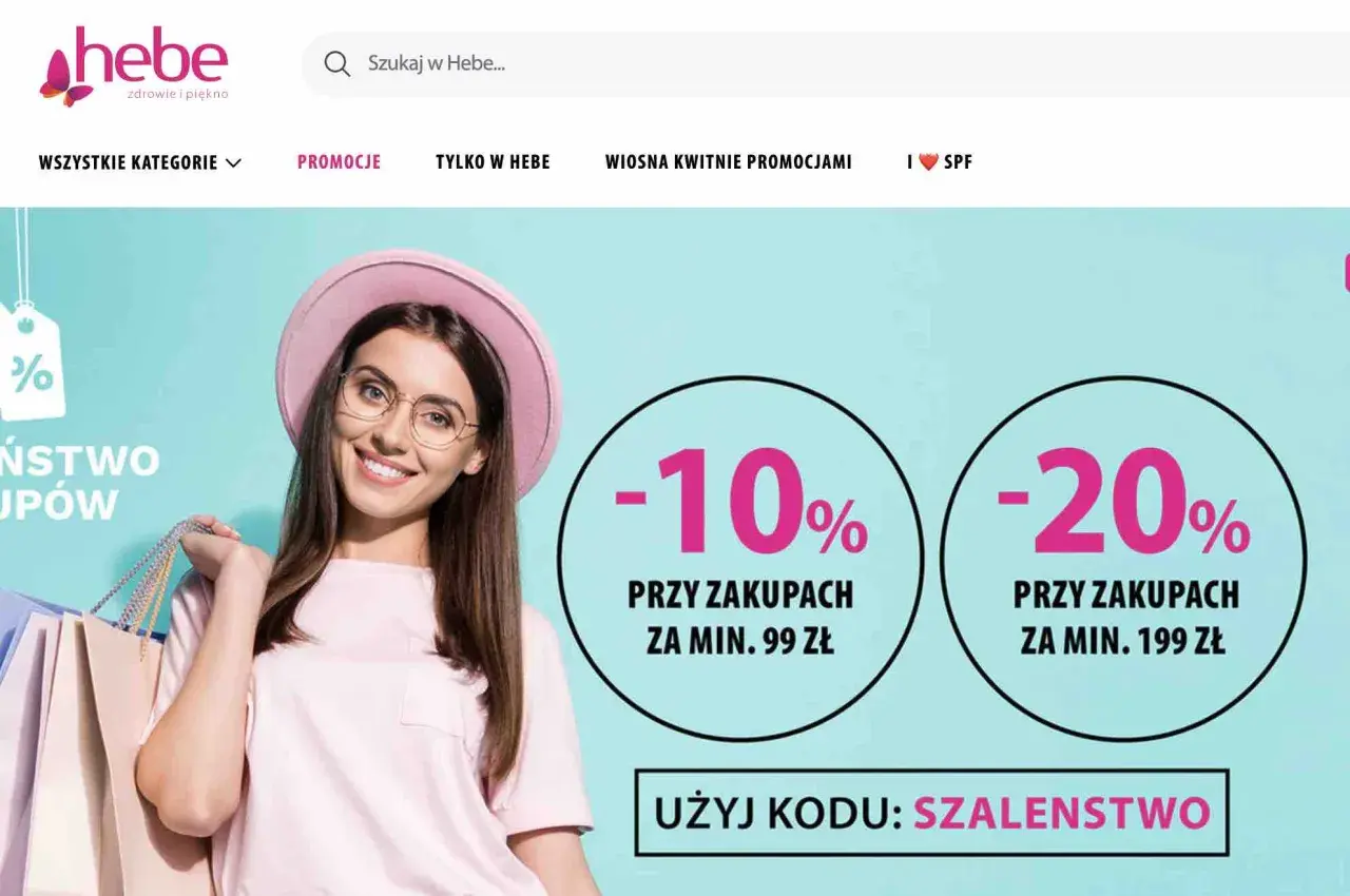 Uśmiechnięta kobieta z torbami na zakupy, promocje -10% i -20% w Hebe.