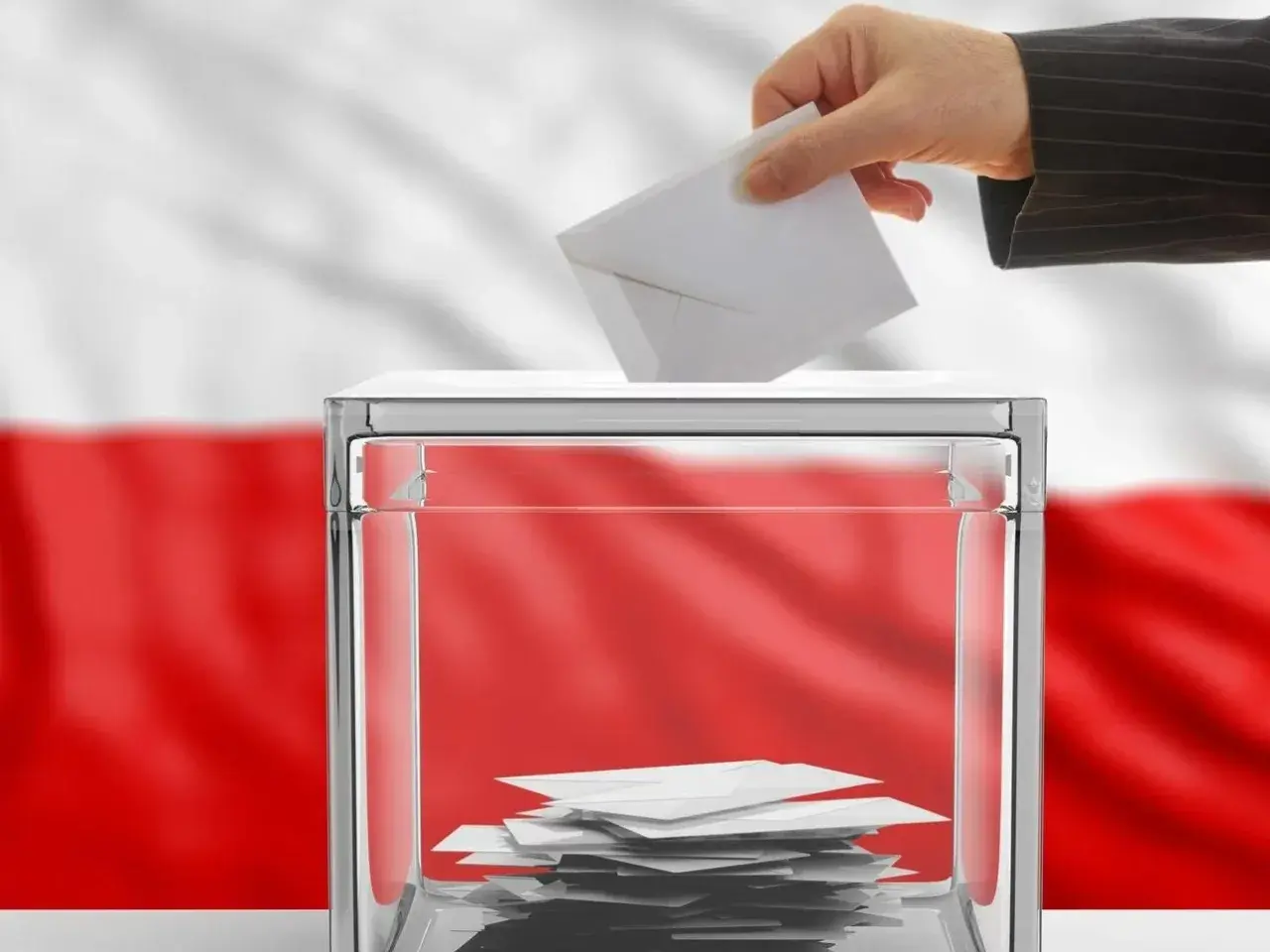 Dłoń wrzuca kartę do urny wyborczej. Polska flaga w tle symbolizuje kraj, od którego można głosować.