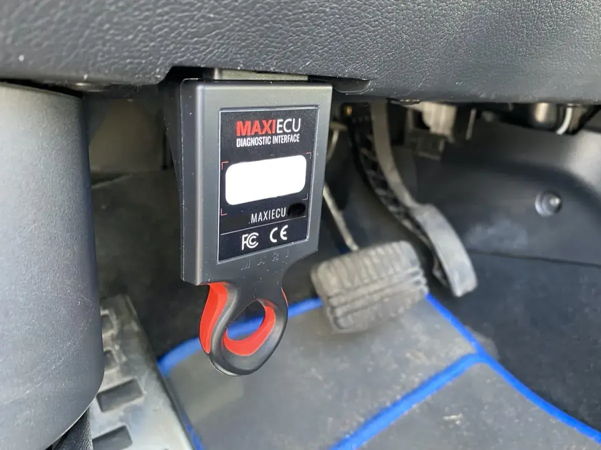 MAXIECU diagnostyczny interfejs do Citroena, podłączony pod deską rozdzielczą, obok pedałów.