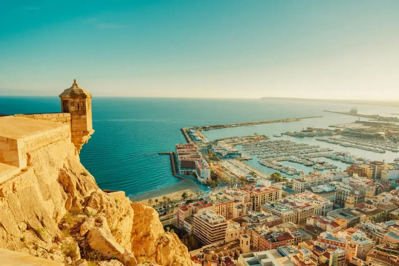 Vista panorámica de Alicante, con su castillo, el puerto deportivo lleno de barcos y el mar azul. Así es cual es la costa blanca.