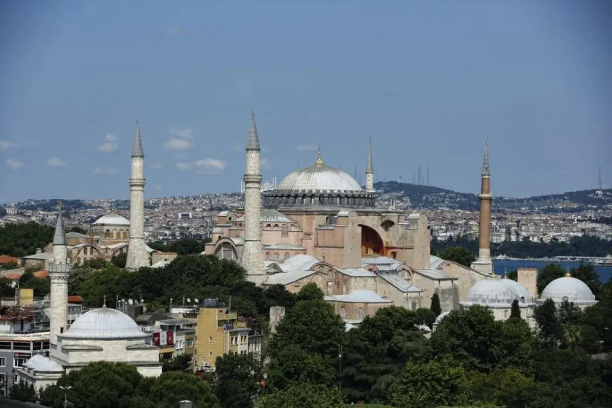 Hagia Sofia i Istanbul, en ikonisk byggnad med kupoler och minareter, reser sig mot en blå himmel.