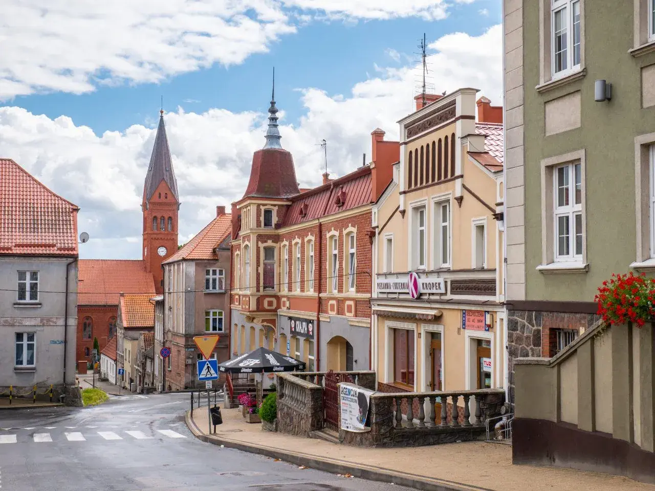 Ulica w gminie Skarszewy z kościołem w tle i kolorowymi kamienicami.