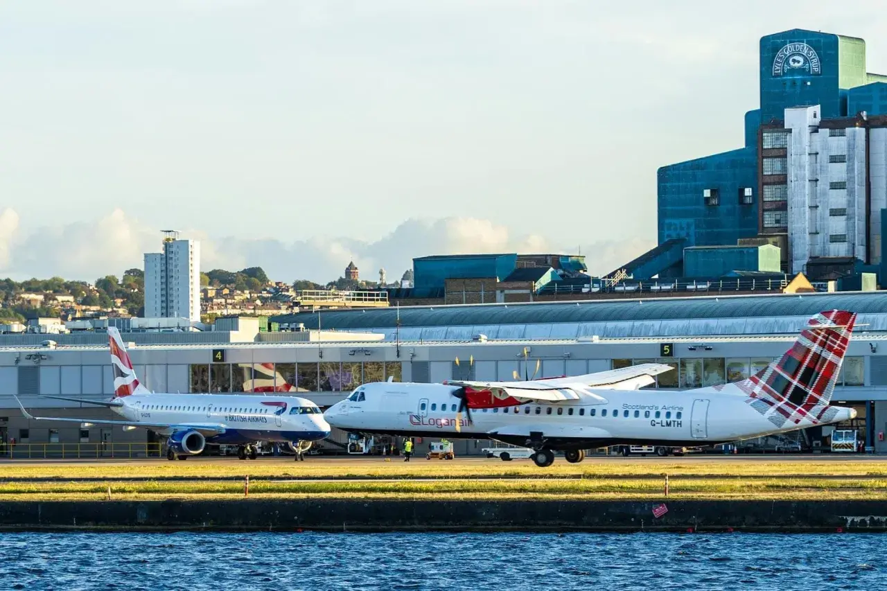 British Airways und Loganair Flugzeuge am London Flughafen. Im Hintergrund die markante Lyle's Golden Syrup Fabrik.