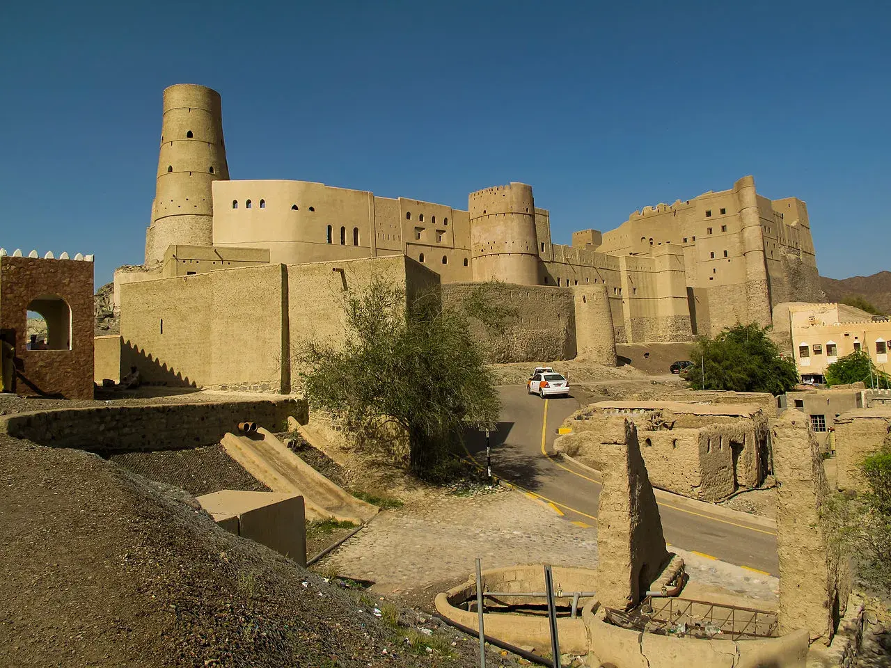 Imponujący fort Bahla w Omanie, z charakterystyczną okrągłą wieżą, góruje nad krajobrazem.