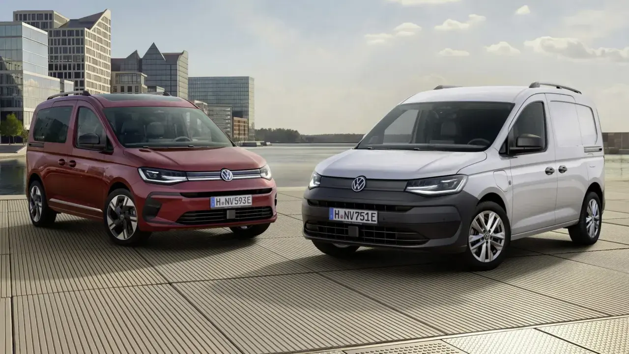 Dwa Volkswageny Caddy 3: czerwony osobowy i biały dostawczy, stoją na tle nowoczesnej architektury i wody.