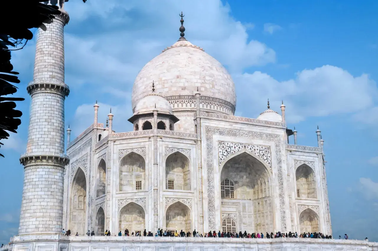 Biały marmur Taj Mahal, jeden z najpiękniejszych zabytków w Indiach, lśni na tle błękitnego nieba.