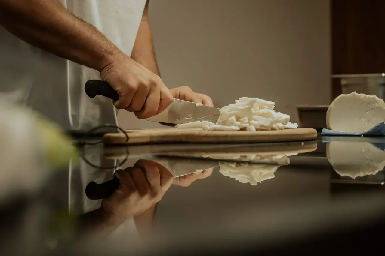 Hände schneiden Fior di Latte Mozzarella für eine Pizza.