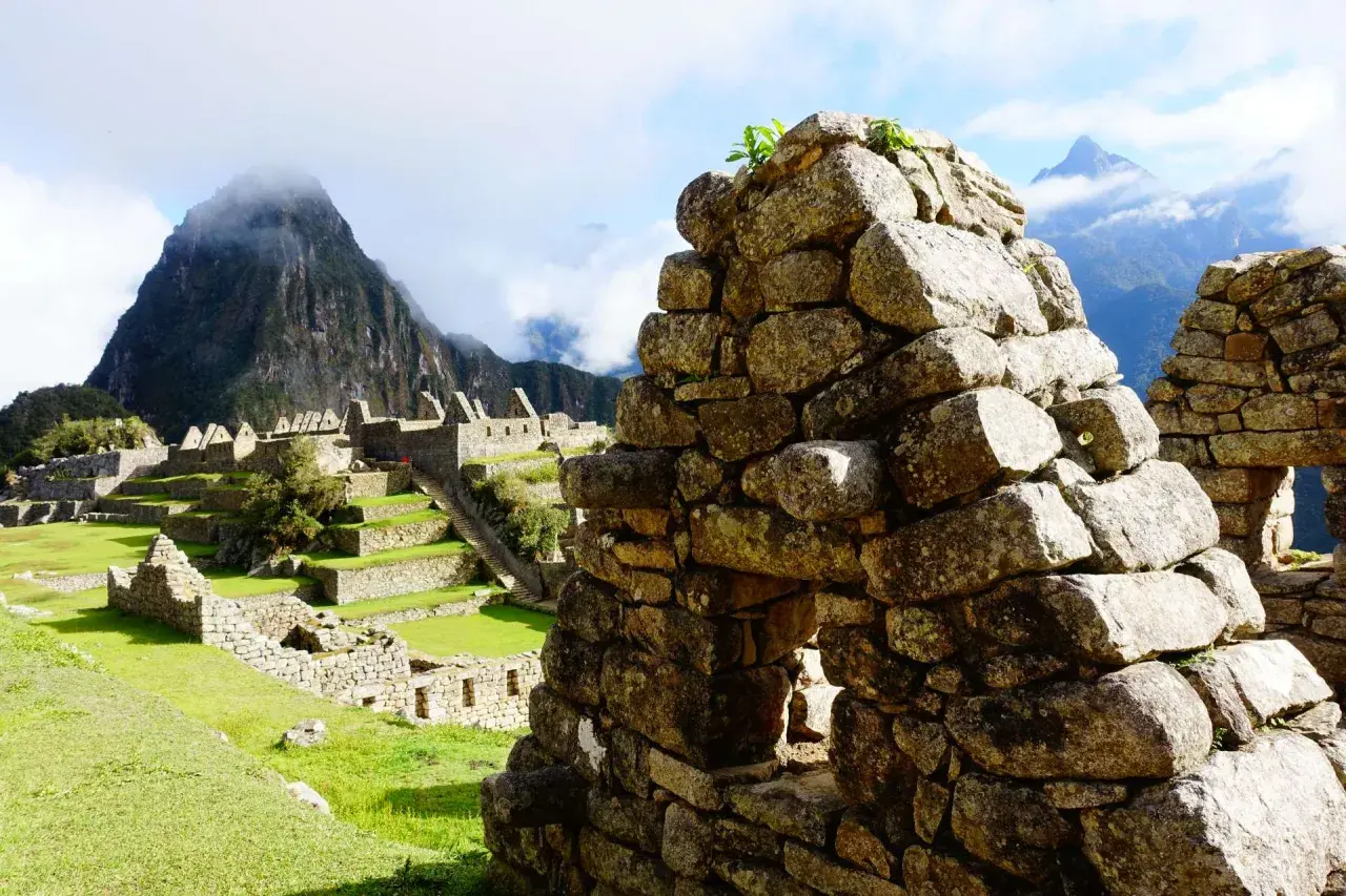Ruinen von Machu Picchu mit terrassierten Feldern und Bergen im Nebel. Die **Andenkreuz Bedeutung spirituell** wird hier durch die Verbindung von Mensch und Natur spürbar.