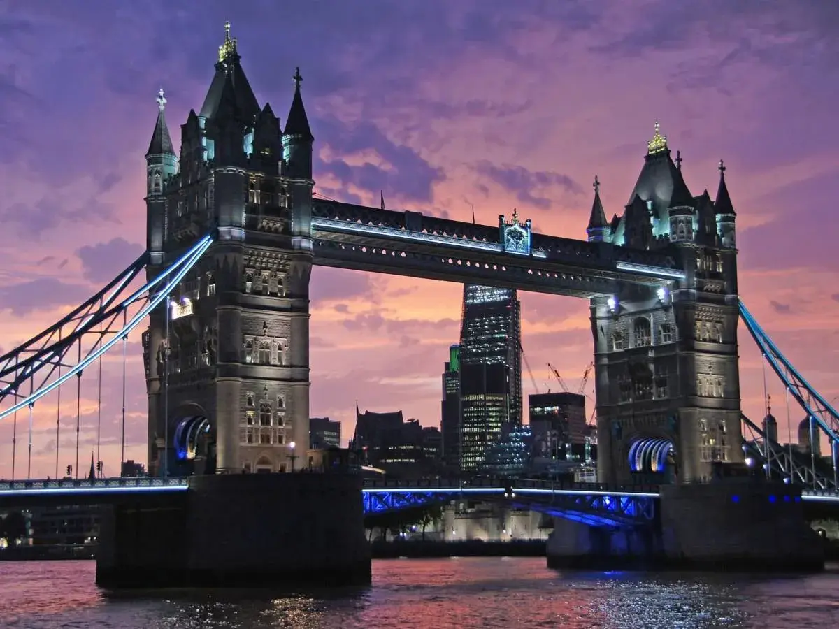Wieczorny widok na Tower Bridge, jeden z najpiękniejszych zabytków w Londynie, z fioletowym niebem w tle.