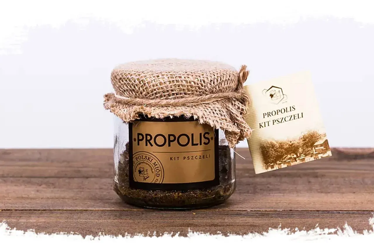 Słoik z propolisem, znanym jako kit pszczeli, z etykietą "PROPOLIS KIT PSZCZELI". Naturalne właściwości tego produktu pszczelego są doceniane od wieków.
