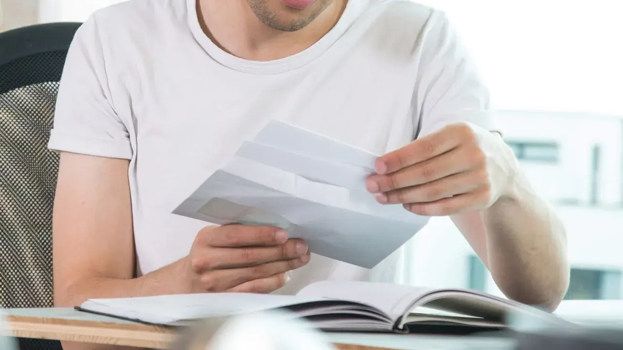 Mann öffnet Briefumschlag, was die Bedeutung von "c/o" in diesem Kontext verdeutlicht.