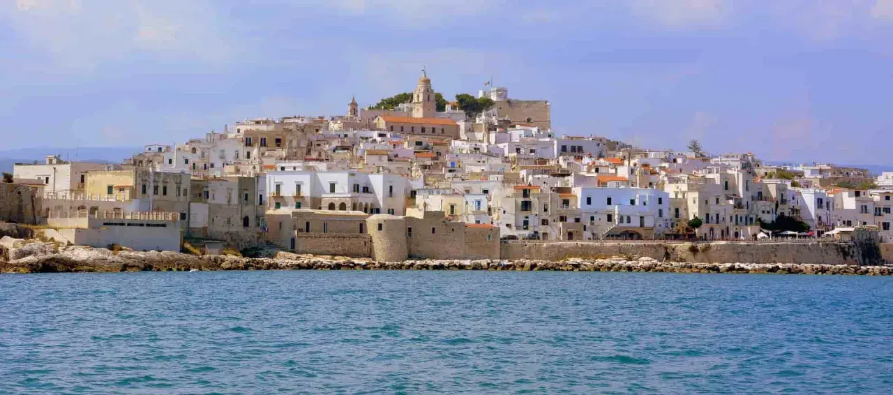 Un borgo bianco a picco sul mare, con un campanile in cima. Ricorda il vino primitivo, significato di sole e terra pugliese.