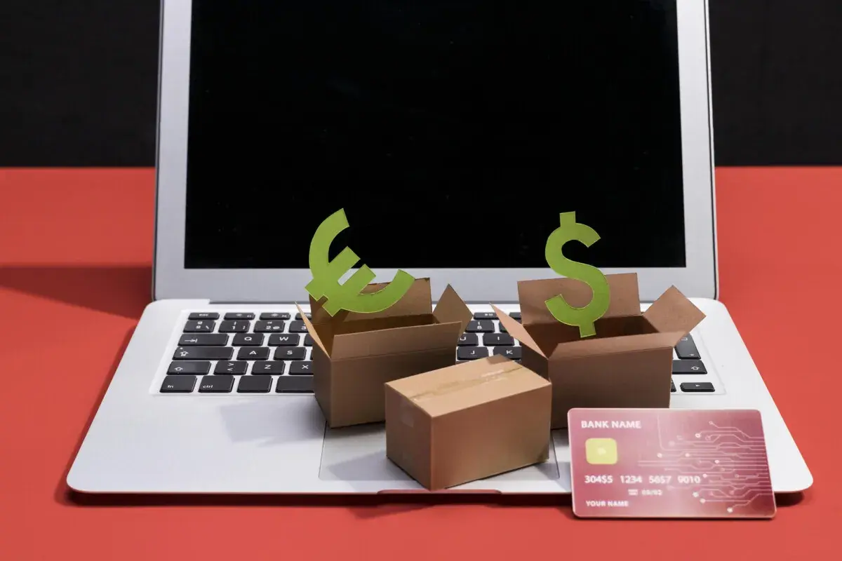 Ideas para como hacer una tienda virtual: cajas, símbolos de euro y dólar, tarjeta de crédito y laptop.