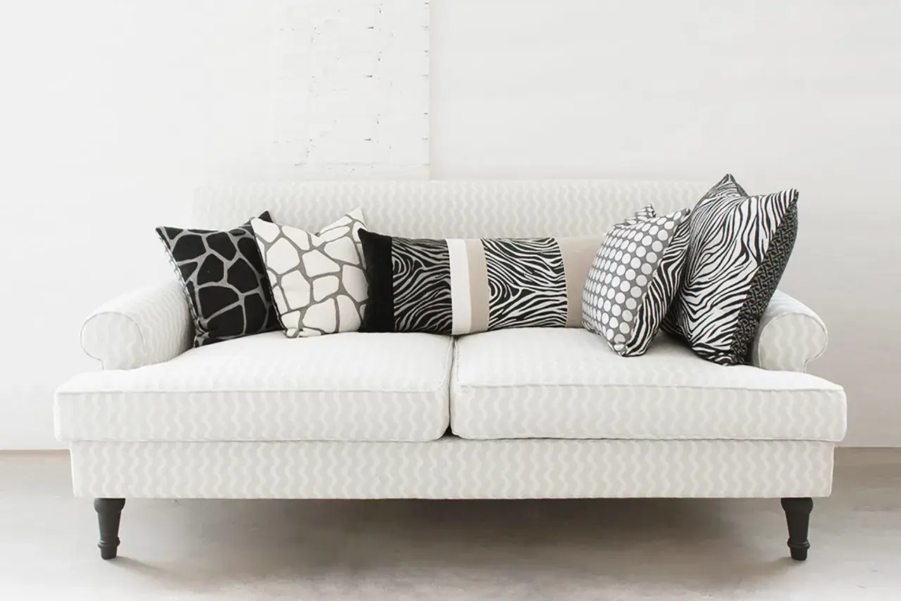 Un divano bianco con cuscini a fantasia animalier e pois: un'idea su come disporre i cuscini sul divano per un tocco moderno.