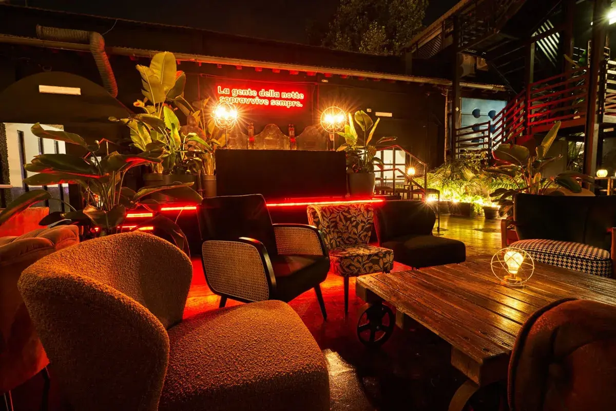 L'anima della birreria: poltrone accoglienti, piante rigogliose e luci al neon rosse creano un'atmosfera vibrante per la notte.