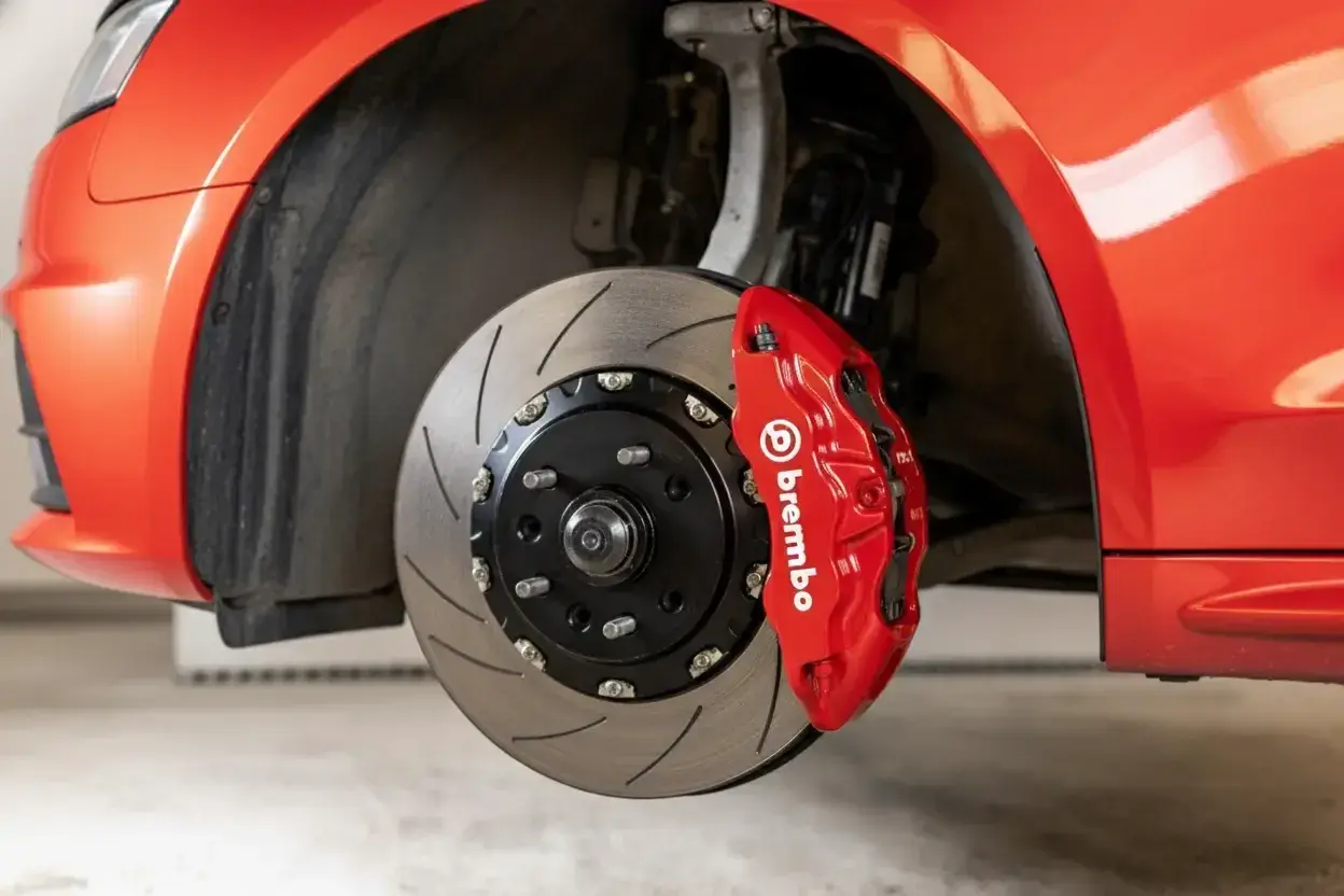 Gros plan sur un étrier de frein Brembo rouge vif sur une voiture de sport. Le disque de frein rainuré est visible. Idéal pour connaître le tarif changement étrier de frein.