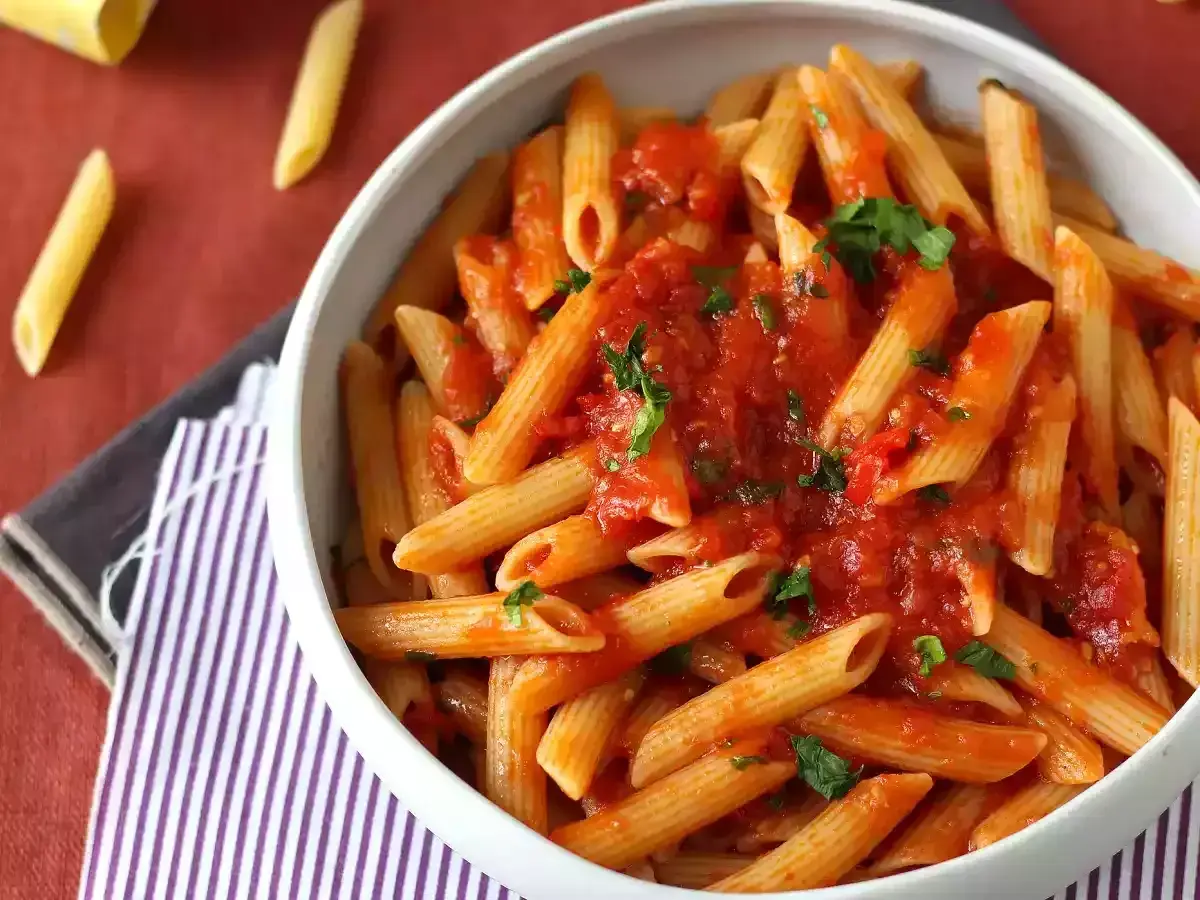En skål med penne pasta arrabiata, toppad med färsk persilja. Enkel och smakrik italiensk klassiker.