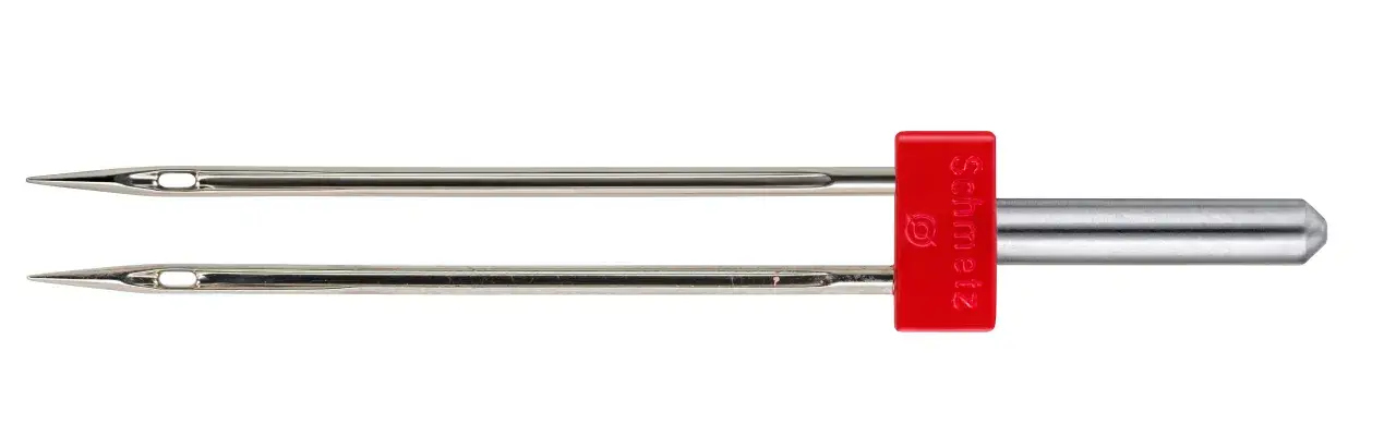 A twin sewing machine needle with a red Schmetz shank. This helps you decide what sewing machine needle to use for decorative stitches.