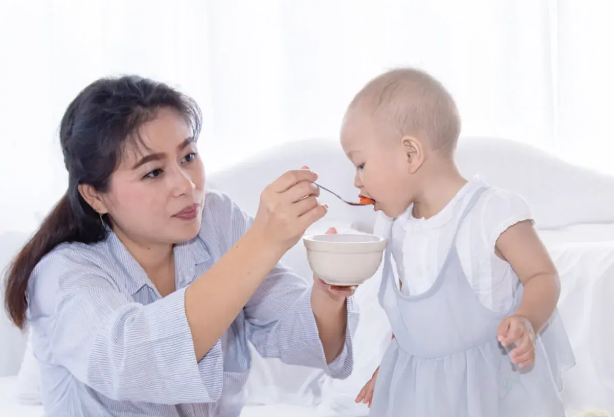 Madre alimenta a su bebé con cuchara. Mi bebé come bien pero no engorda, aunque se ve feliz y saludable.