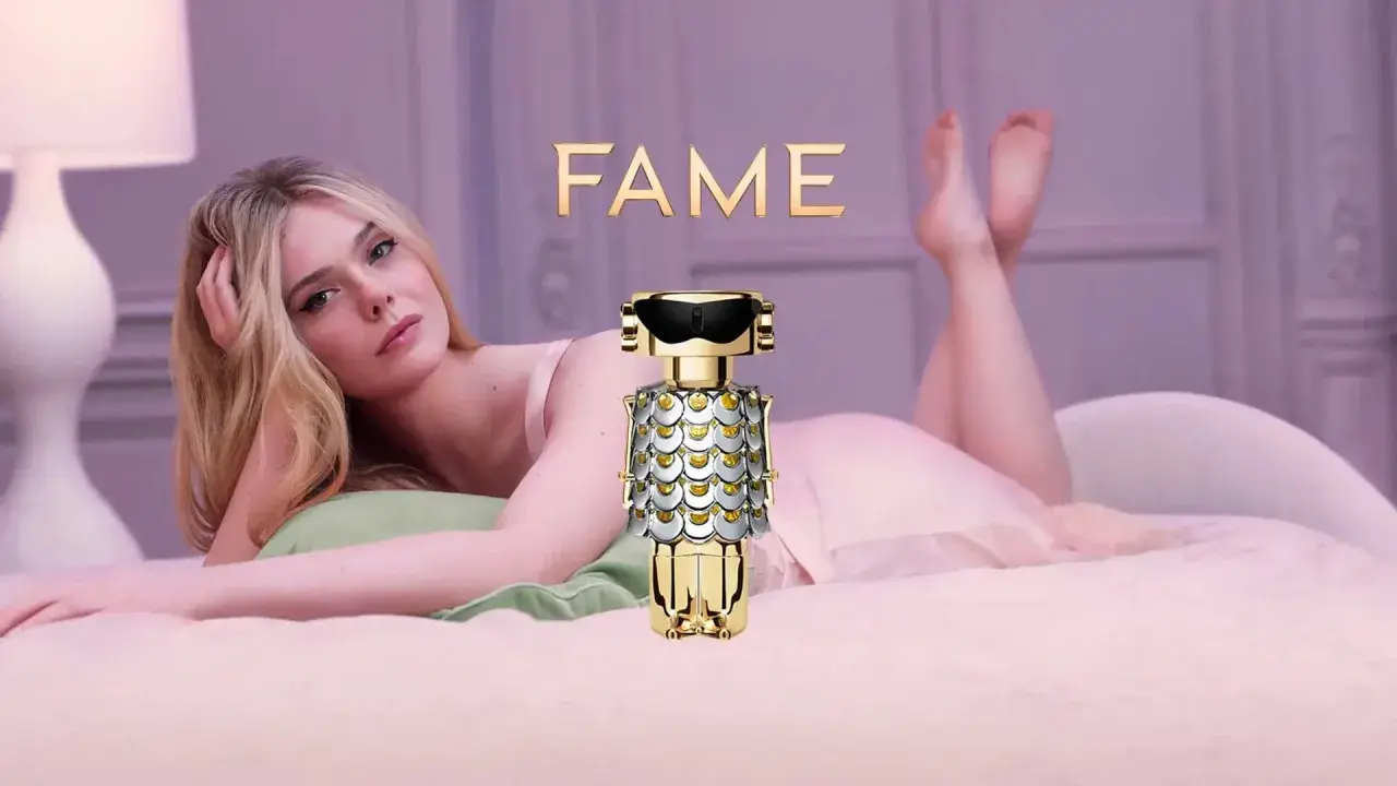 Elle Fanning w łóżku z flakonem perfum FAME Paco Rabanne.