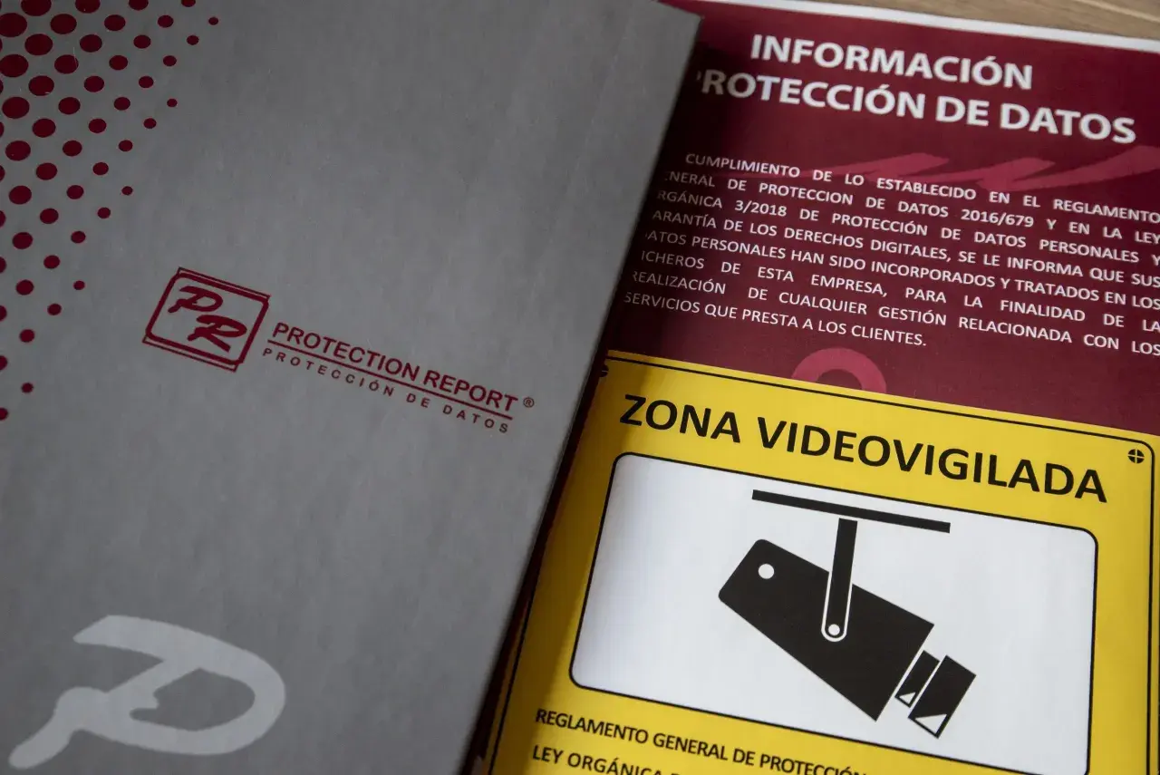 Documentos sobre protección de datos y un cartel de "Zona Videovigilada", parte de una feria de seguridad.