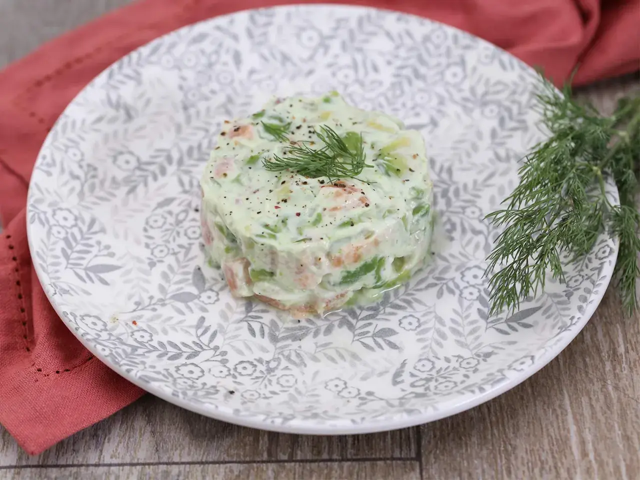 Délicieux tartare de saumon avocat, garni d'aneth frais et servi sur une assiette ornée.