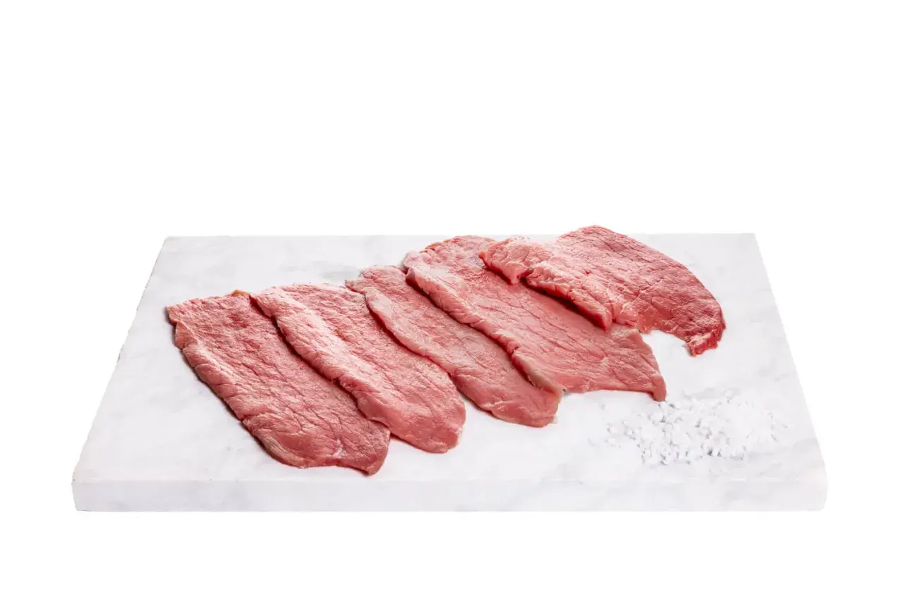 Fettine di vitello pronte per gustose ricette. Carne fresca su tagliere di marmo con sale grosso.