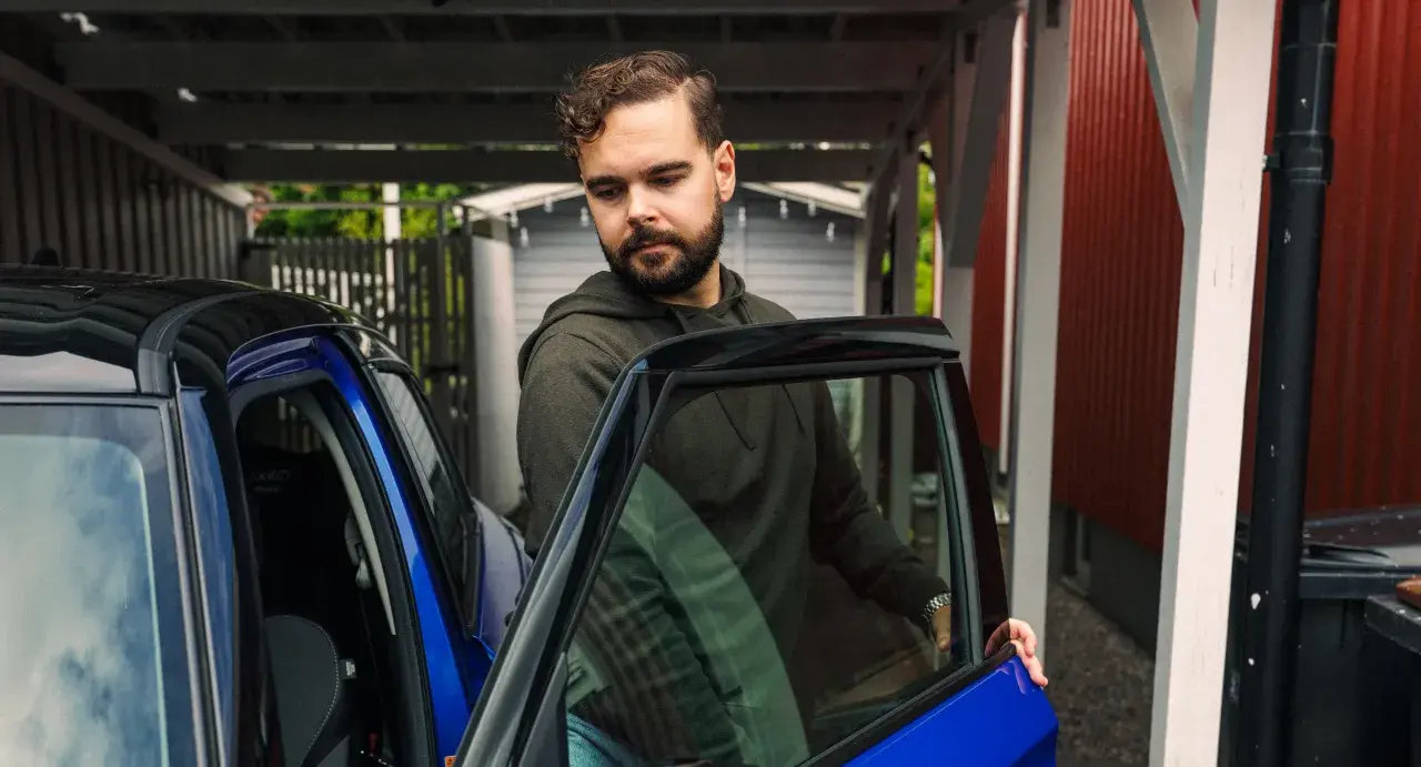 Man med skägg öppnar dörren till en blå bil. Kanske dags att tänka på att måste man serva bilen varje år för att den ska hålla sig i toppskick.
