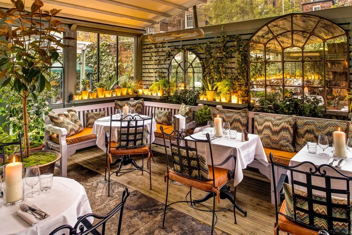 Gemütliche Terrasse mit Tischen, Kerzen und Pflanzen. Einladendes Ambiente für ein schönes Essen. Design und Genuss vereint.
