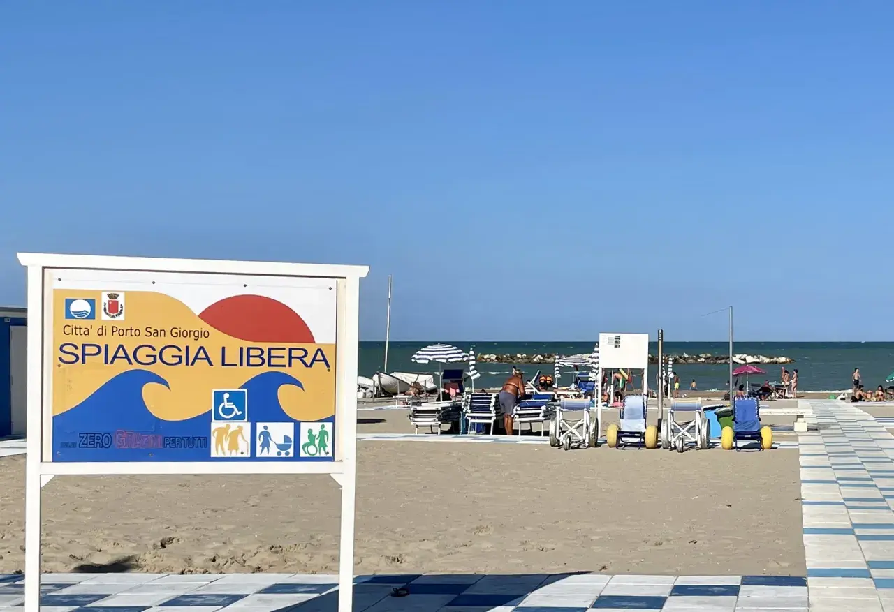 Cartello "Spiaggia Libera" a Porto San Giorgio, con simboli per accessibilità e famiglie.