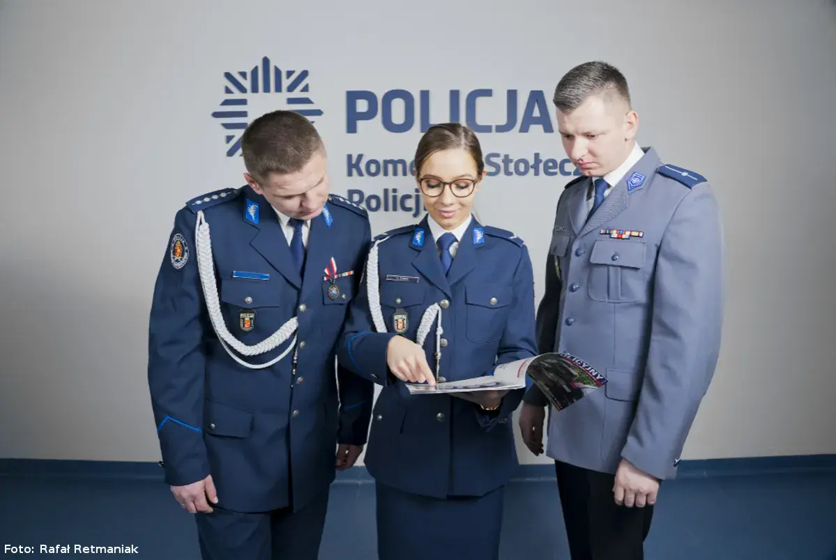 Policjanci w mundurach omawiają materiały. Pokazują, jak nosić furażerkę policja.